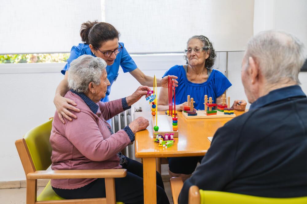 A nurse assists elderly residents while playing memory games in a memory care facility near Lewiston, MN.